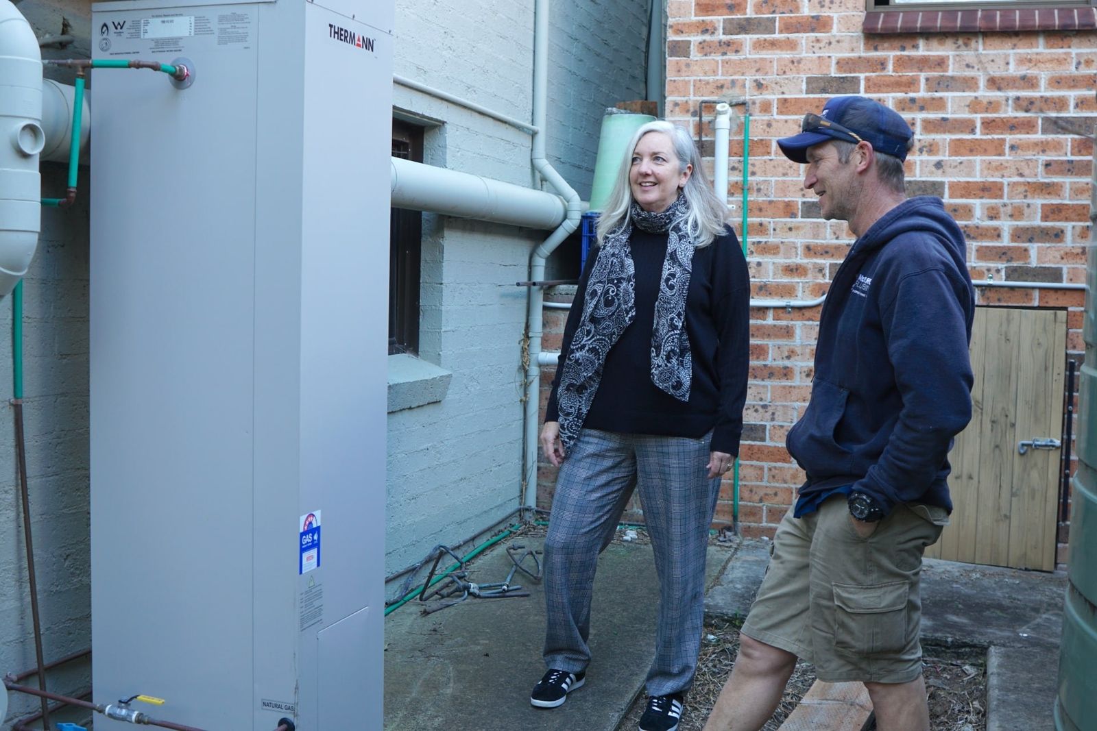 Plumber and customer checking the gas and hot water outside a house
